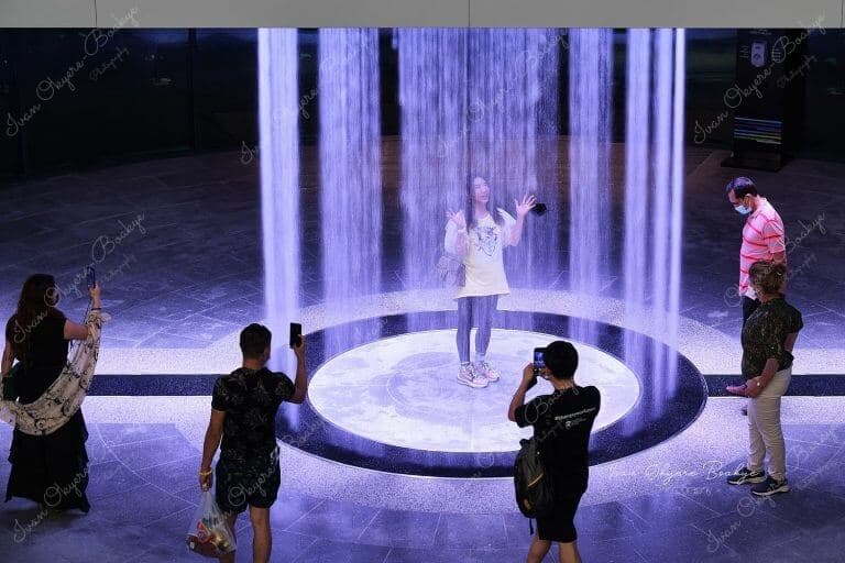A woman standing in a waterfall in the Kingdom of Saudi Arabia Pavilion in the Opportunity District section of the Dubai Expo 2020, Dubai, UAE