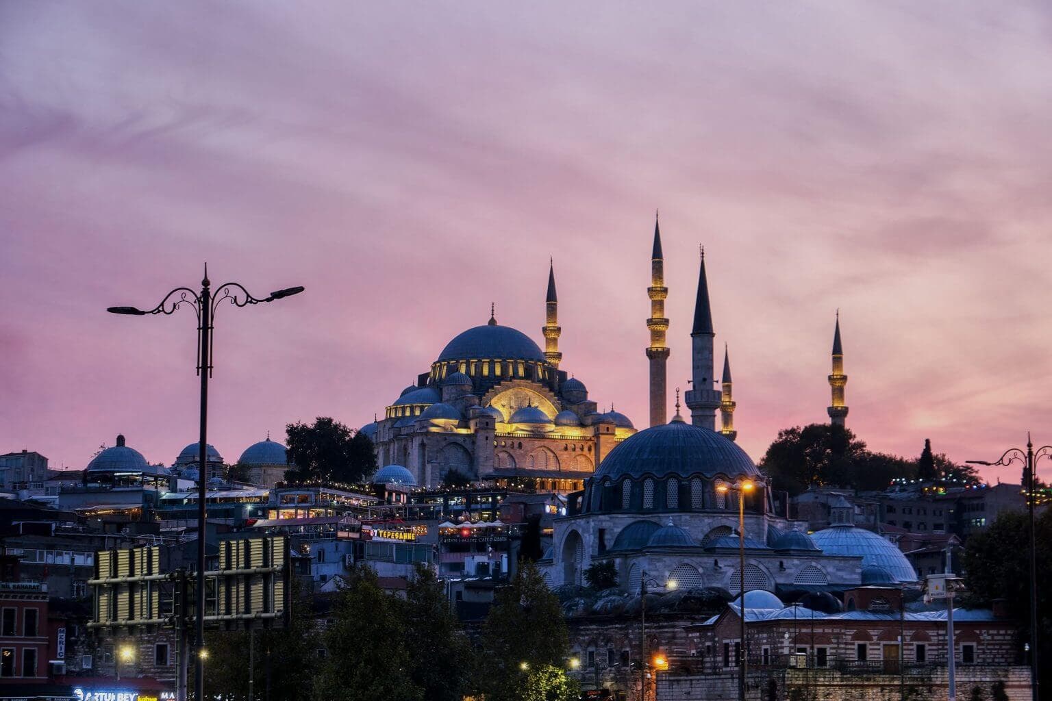View of illuminated Suleymaniye Mosque at sunset from Eminonu harbour, Istanbul, Turkey
