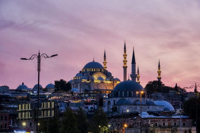 View of illuminated Suleymaniye Mosque at sunset from Eminonu harbour, Istanbul, Turkey
