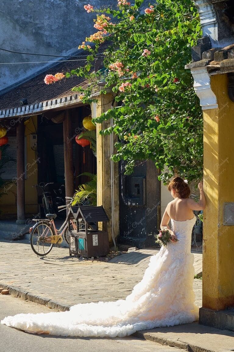 Urban photo shoot of Vietnamese bride in an elegant white wedding dress in the colourful streets of Hoi Ann Old Town in Vietnam
