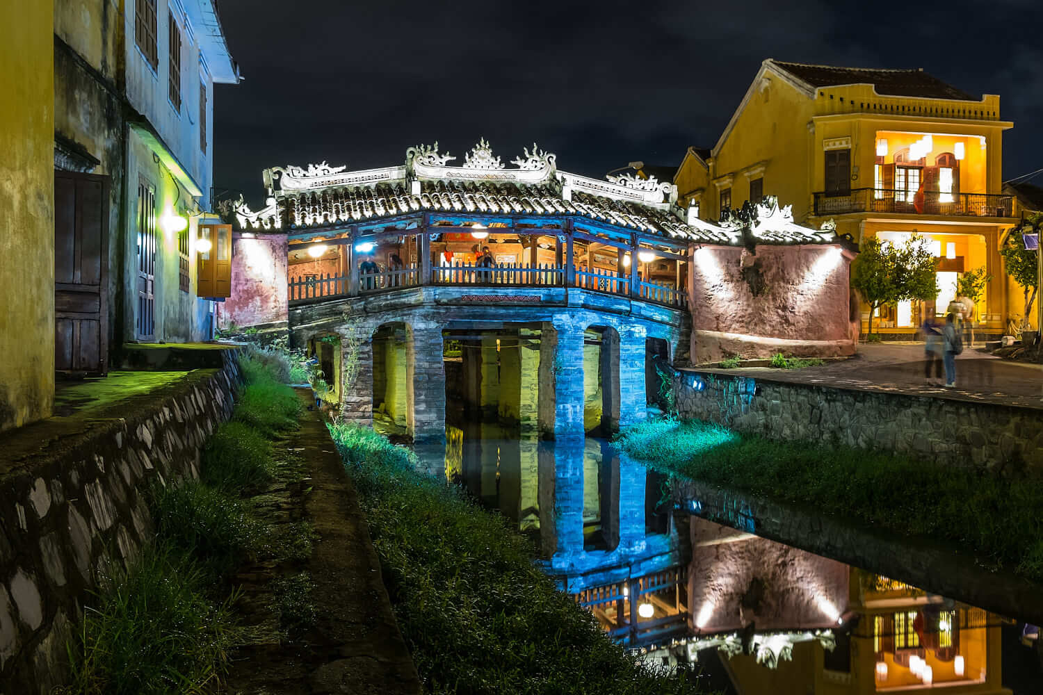 The amazingly colourful and beautiful Japanese Covered Bridge (Cau Nhat Ban) at night with reflection in the Thu Bon River in Hoi An Old Town, Vietnam