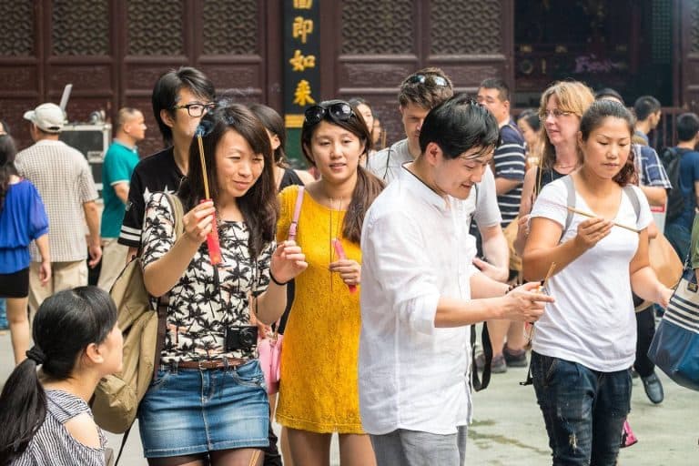 Visitors holding lit incense at Jade Buddha Temple, Shanghai, China