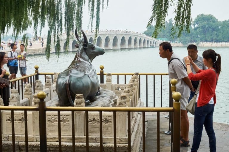 Cow statue and 100 arch bridge in background, Kunming Lake, Beijing, China