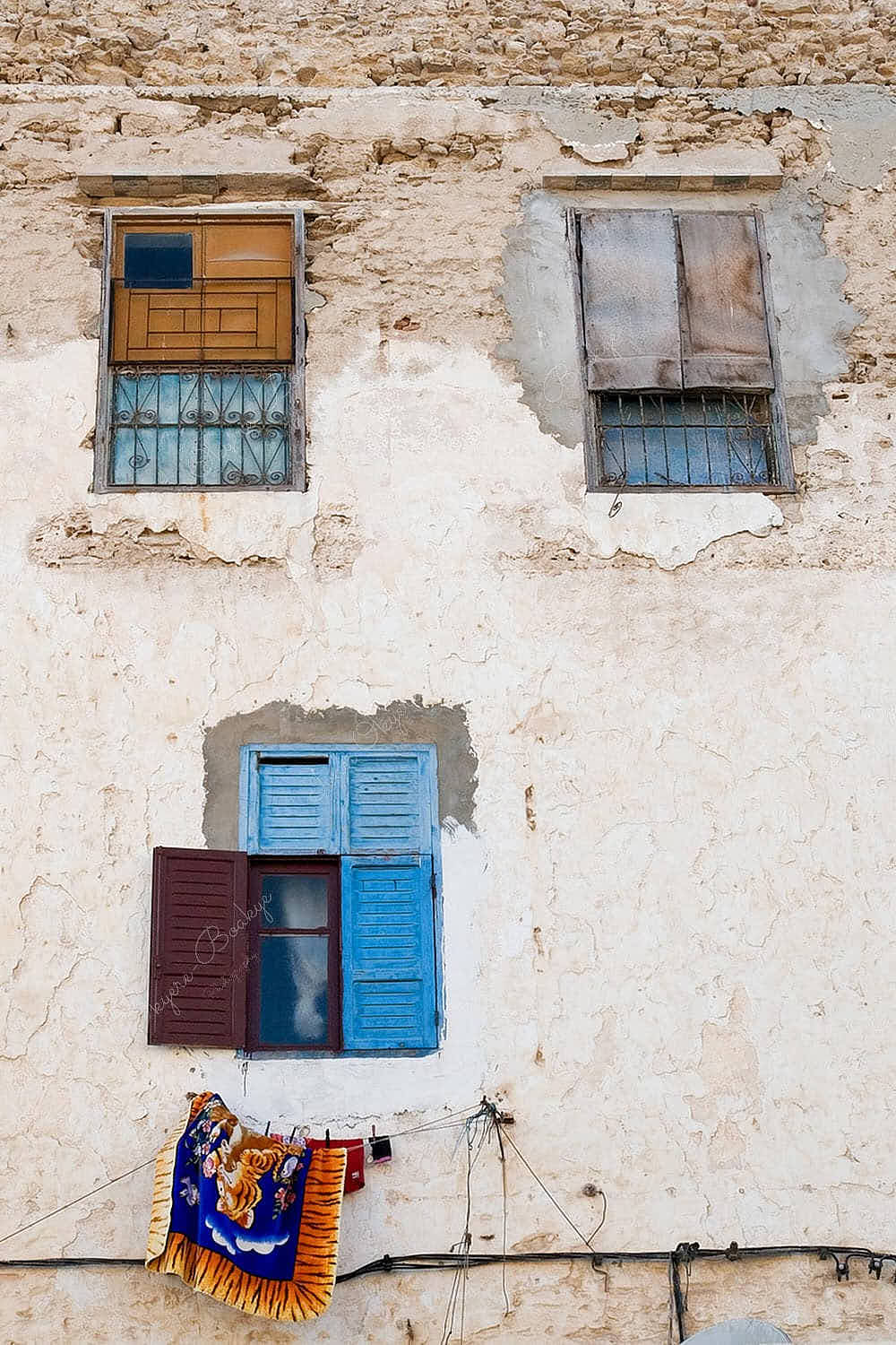 Weathered windows and hanging carpet in Essaouira, Morocco