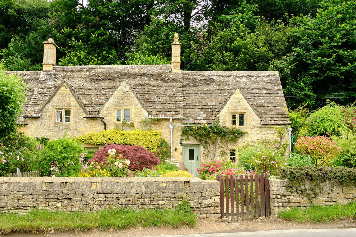 Traditional English stone cottage with picturesque flower garden in Bibury, Gloucestershire, England, UK