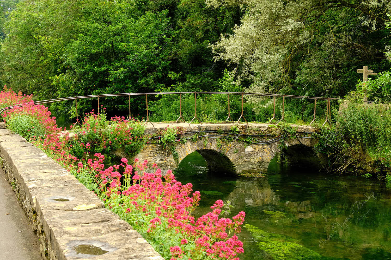Stone bridge over the River Coln to the Arlington Row cottages in Cotswold village of Bibury, England, UK