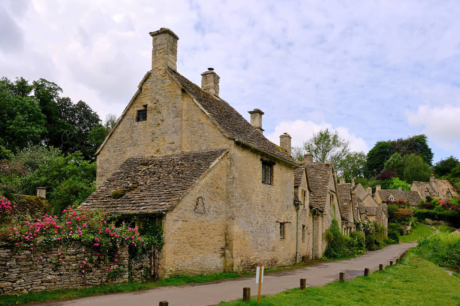 View from footpath leading past the famous picturesque Arlington Row Weavers Cottages, Bibury, Cotswolds, England, UK
