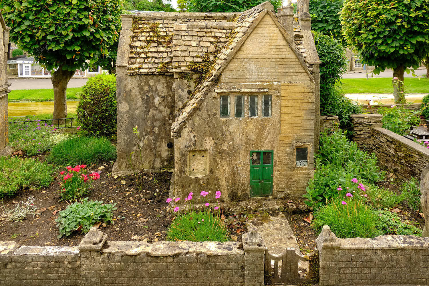 Elevated standing view of a miniature replica traditional English stone cottage and garden in Bourton on the Water Model Village, England, UK