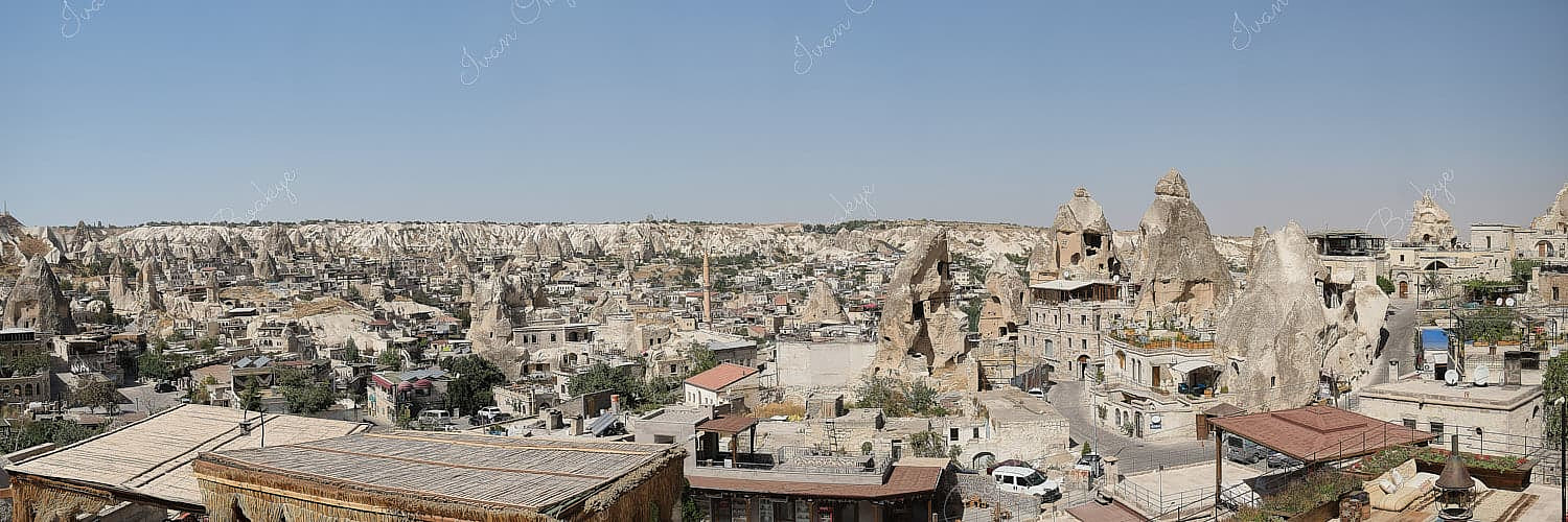 Panoramic view of boutique cave hotels and fairy chimney ruins with Goreme town centre and hills in the background, Cappadocia, Turkey