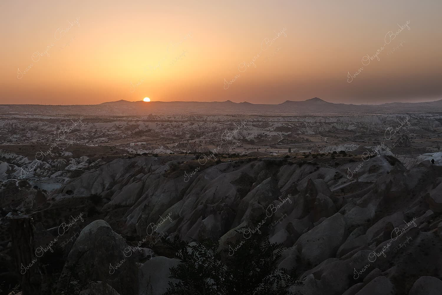 View from the Red Valley Panorama Lookout of Cappadocia rock formations landscape with the sun setting on the horizon, Cappadocia, Turkey
