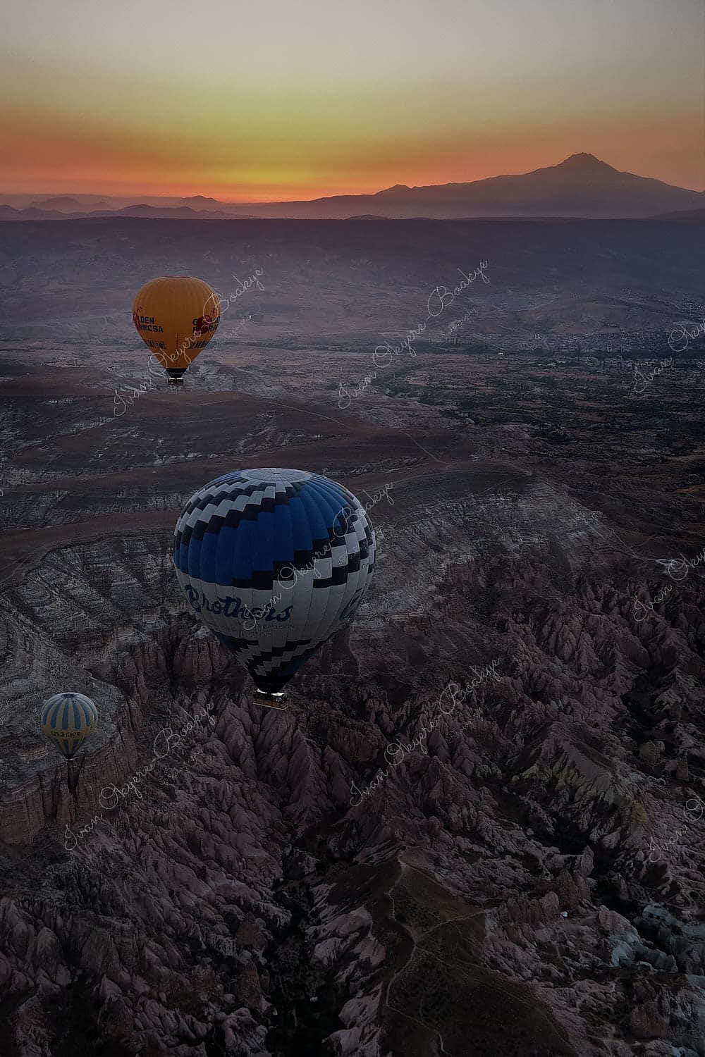 Hot air balloons floating at sunrise over the rock formations landscape of Cappadocia, Turkey
