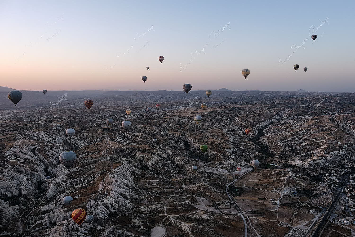 Hot air balloons floating at sunrise over the rock formations landscape of Cappadocia, Turkey