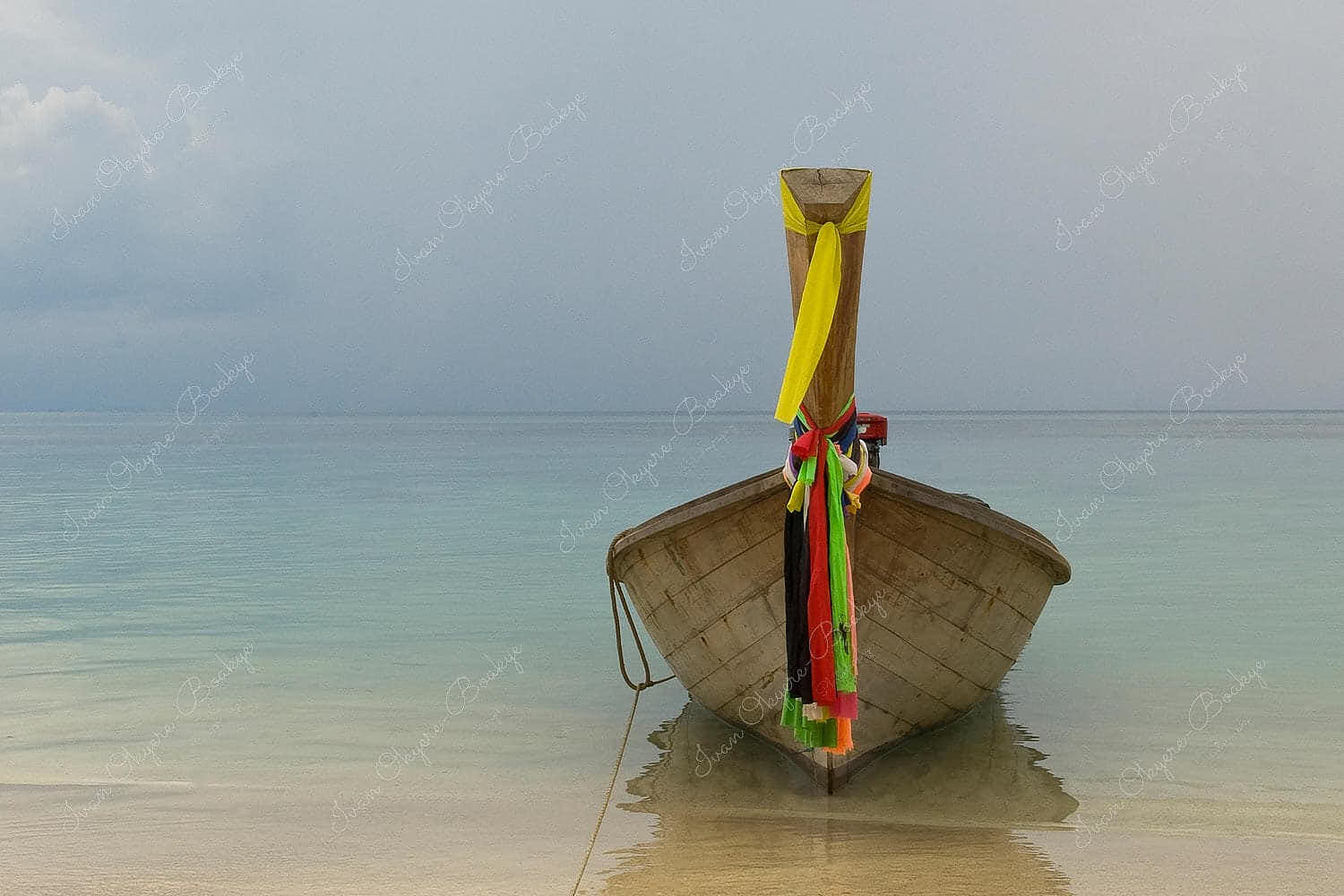 A moored Longtail Boat with colourful pieces of silk cloth tied to the bowsprit at Phi Phi beach, Thailand