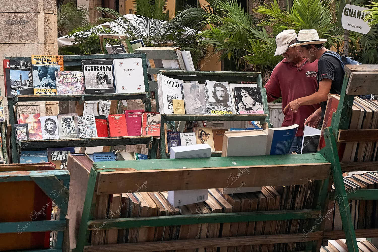 Cubans browsing through second hand books about the Cuban Revolution and heroes including Che Guevara at an outdoors book stall in Plaza De Armas, Habana Vieja, Cuba