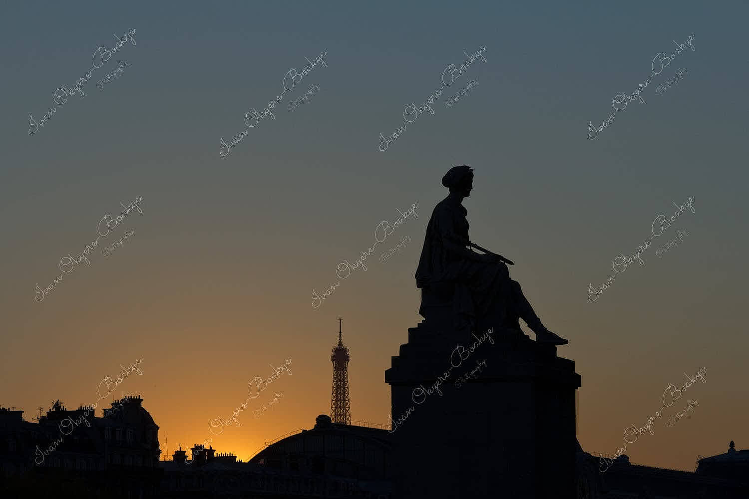 Partial silhouette of a female statue side profile at sunset with the Eiffel Tower in the background, Paris, France