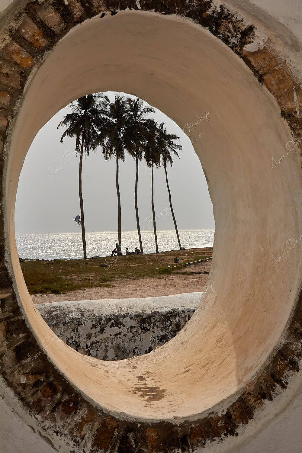 View of palm trees and sea through a stone window at Elmina Castle, Elmina, Ghana