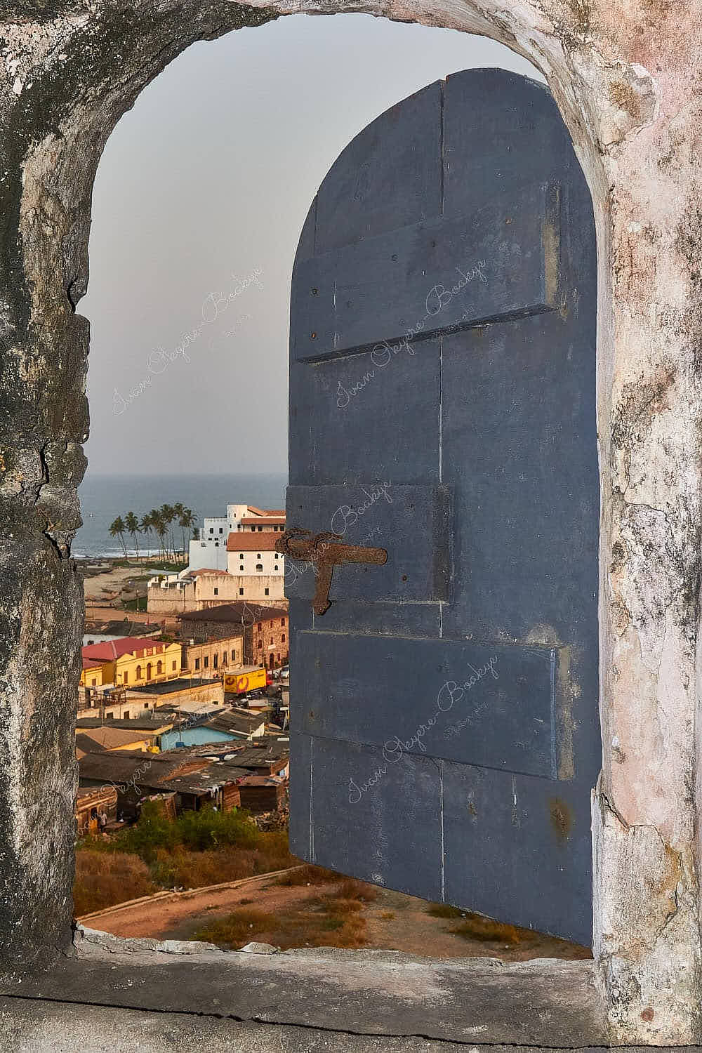 View of buildings and the sea through a stone window at Elmina Castle, Elmina, Ghana
