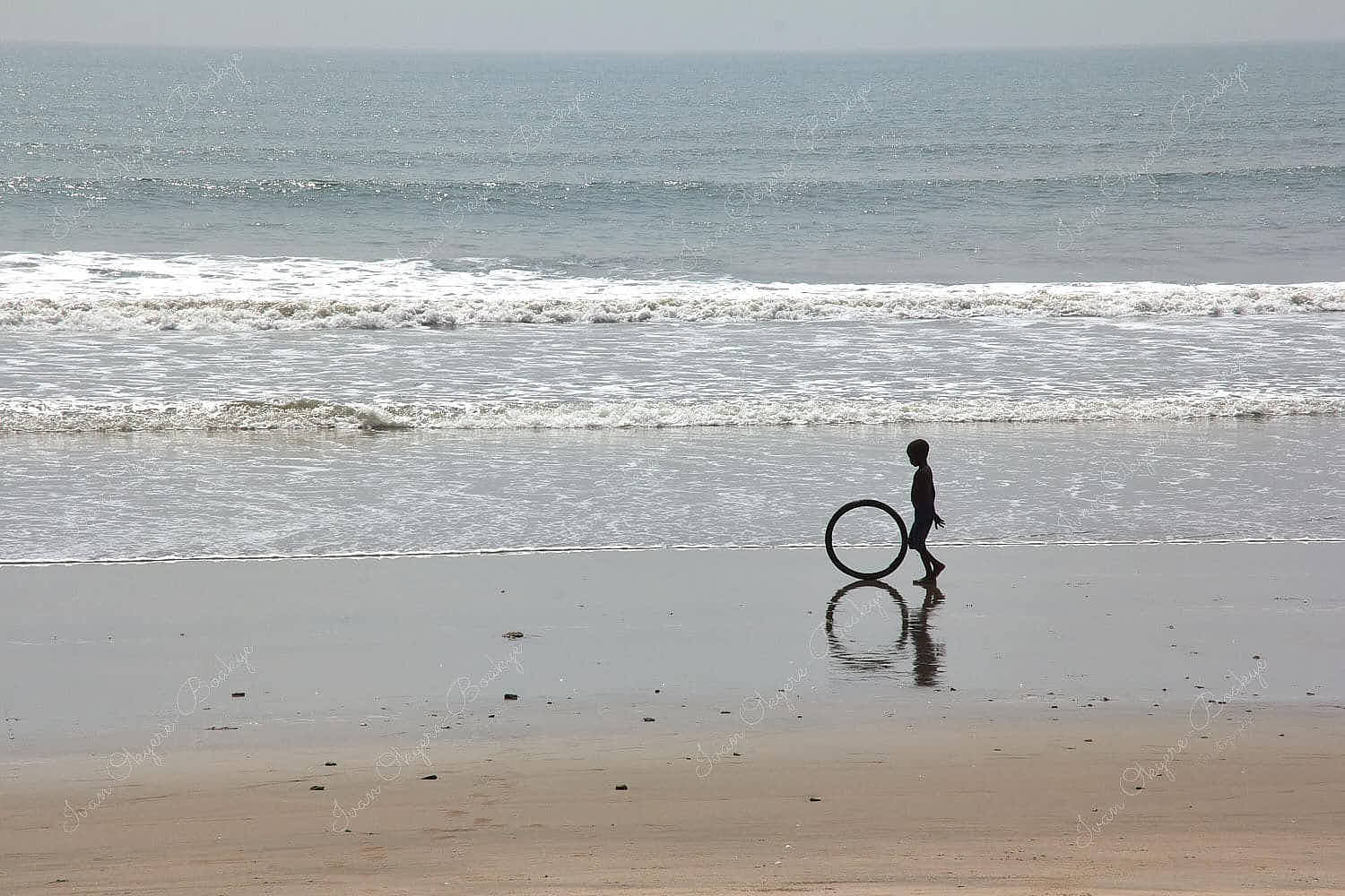 Boy rolling bicycle tyre at Kokrobite Beach, Ghana