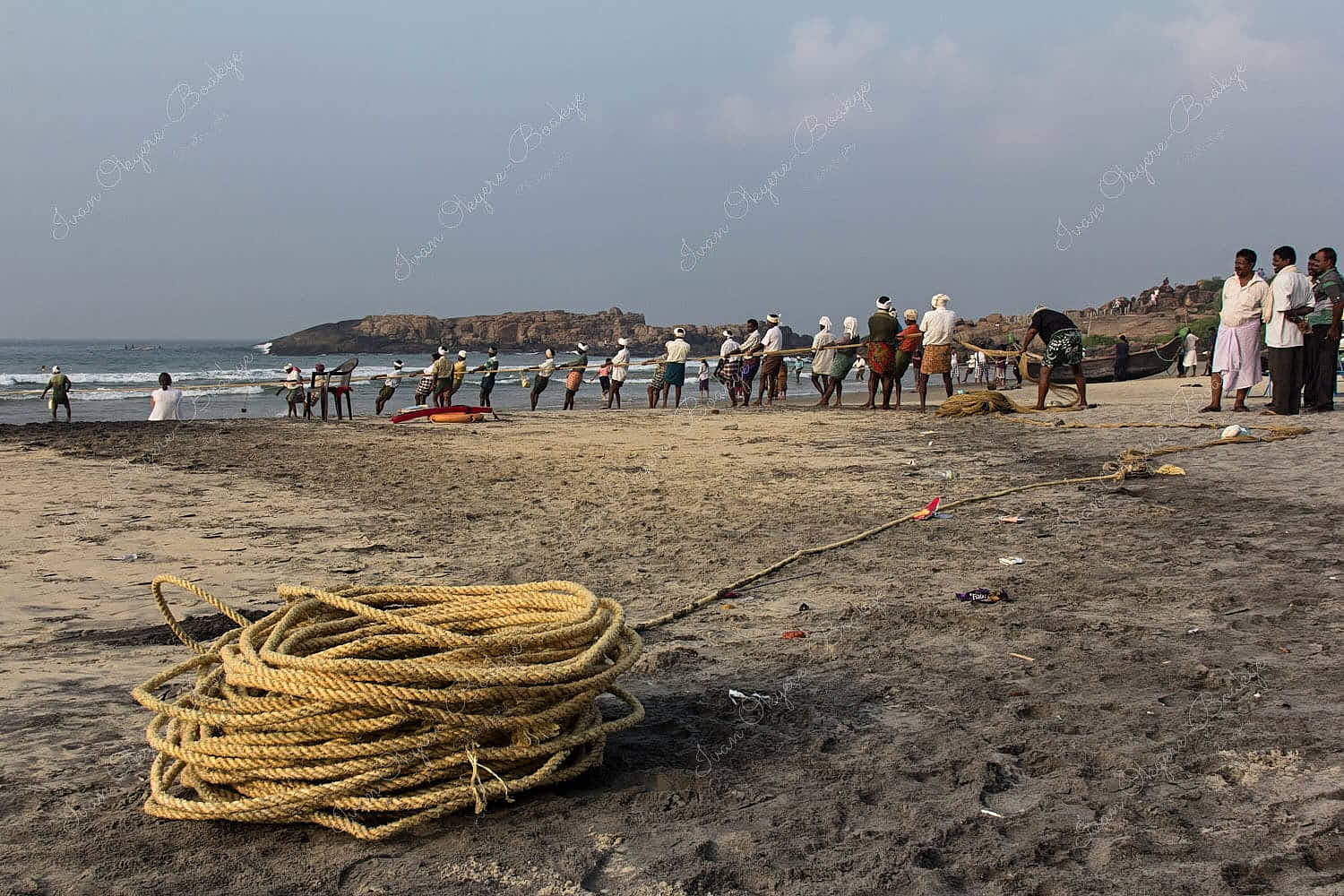 Fishermen pulling in fishing net in Lighthouse Beach in Kovalam, Kerala, India