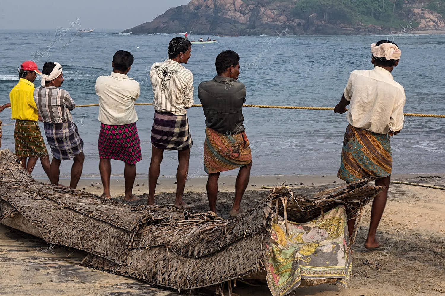 Fishermen pulling in fishing rope at Lighthouse Beach in Kovalam, Kerala, India
