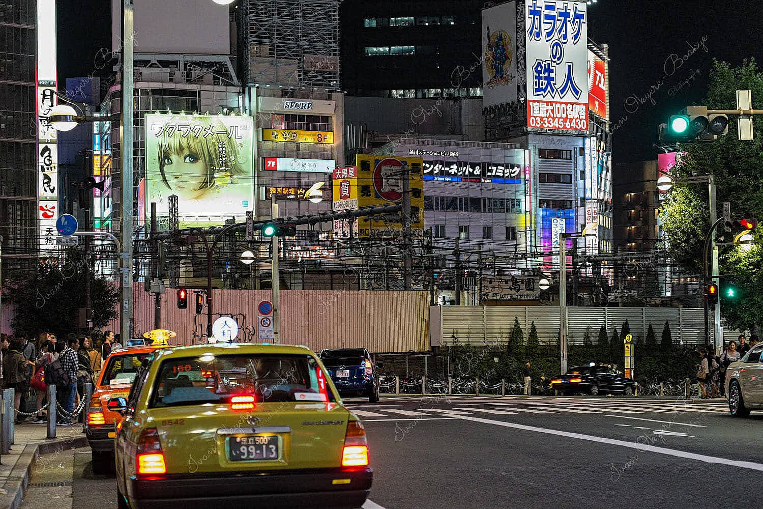 Japanese taxis waiting near a white zebra crossing with large neon advertising billboards on the surrounding buildings in Tokyo, Japan