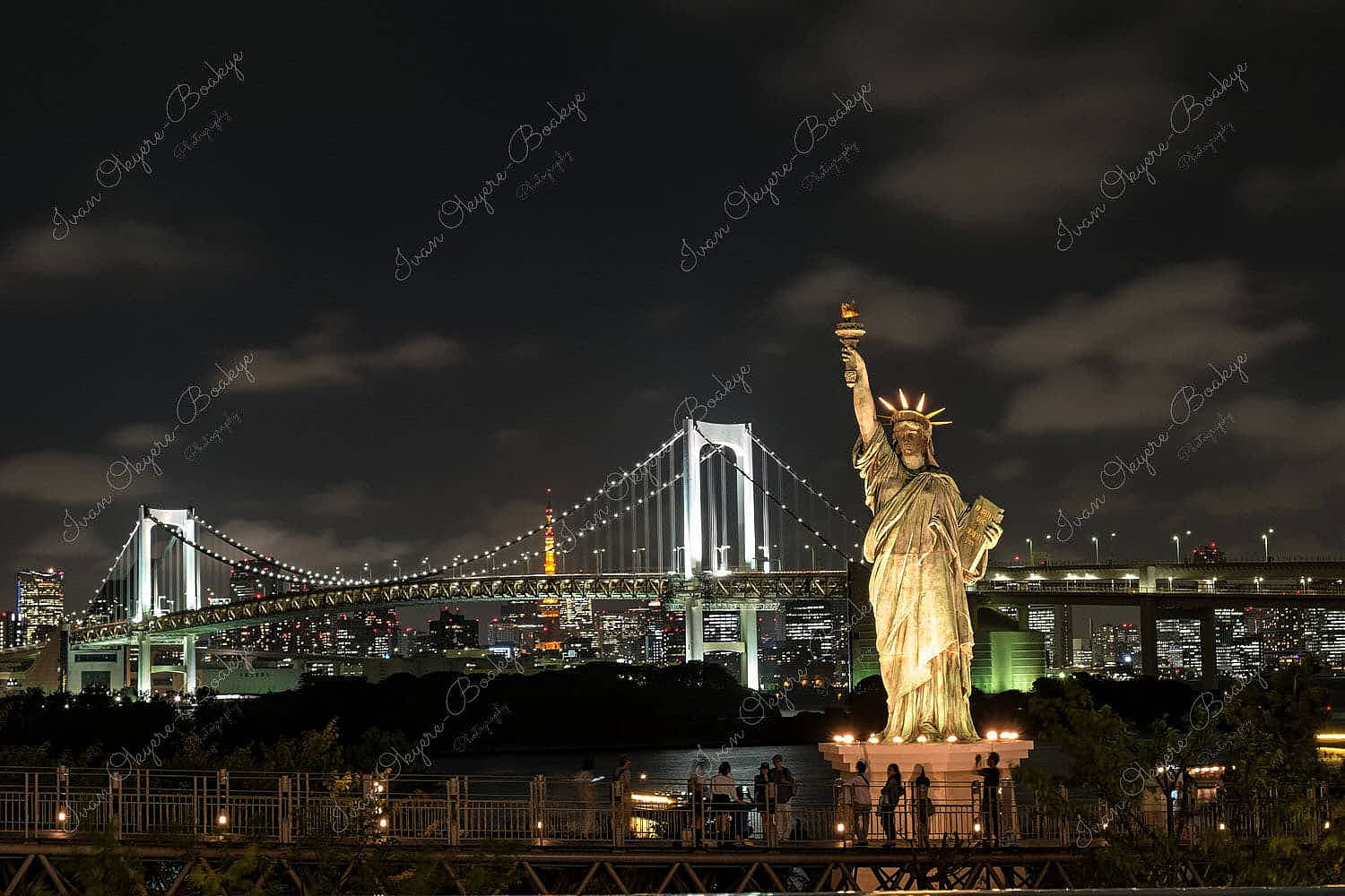 Night view from Odaiba of the illuminated Statue of Liberty, Rainbow Bridge and Tokyo Tower in the distance in Tokyo, Japan