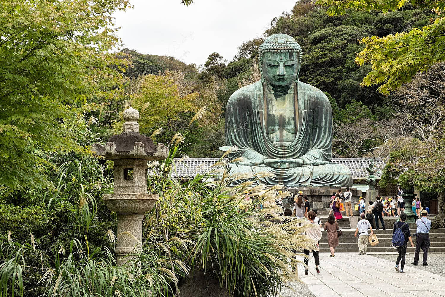 The Great Buddha of Kamakura (Daibutsu) with stone lantern in foreground at Kōtoku-in Temple, Kamakura, Japan