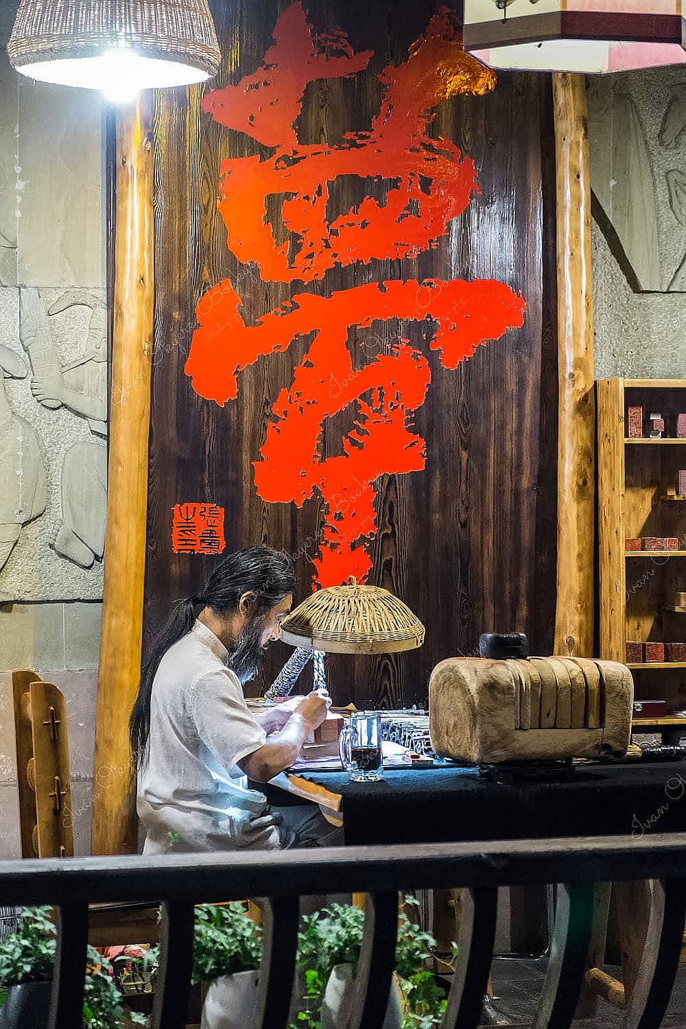 Chinese artist working under a lamp in his streetside office in Gaoping Qu, Nanchong, China
