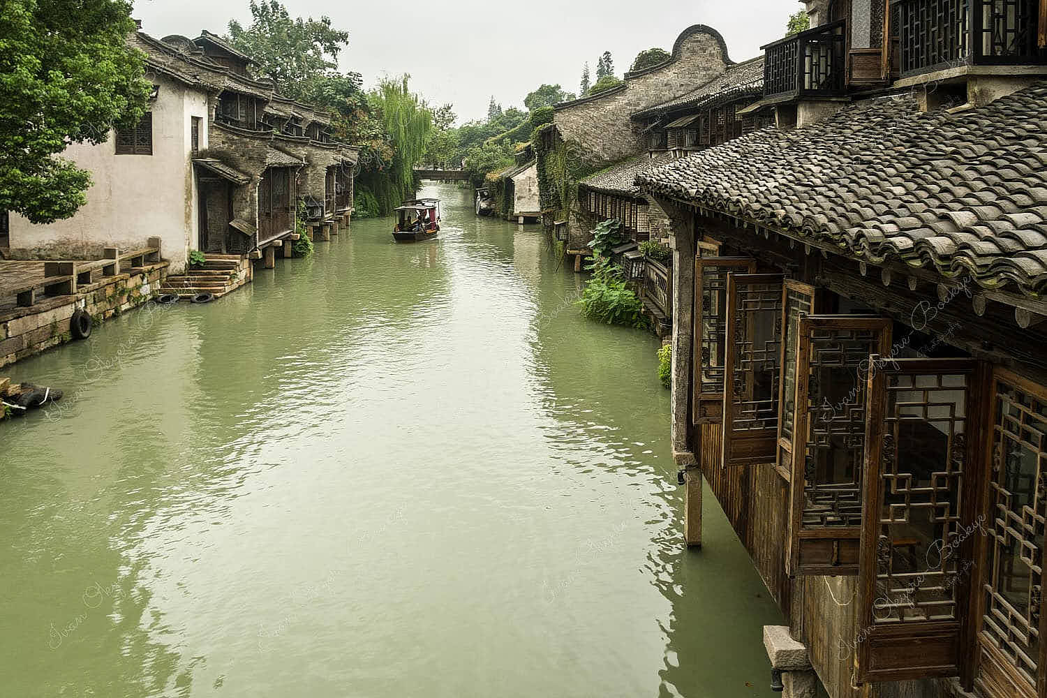 Stone bridge and gondola on the canal running between traditional Chinese houses in the historic scenic Wuzhen water town, China