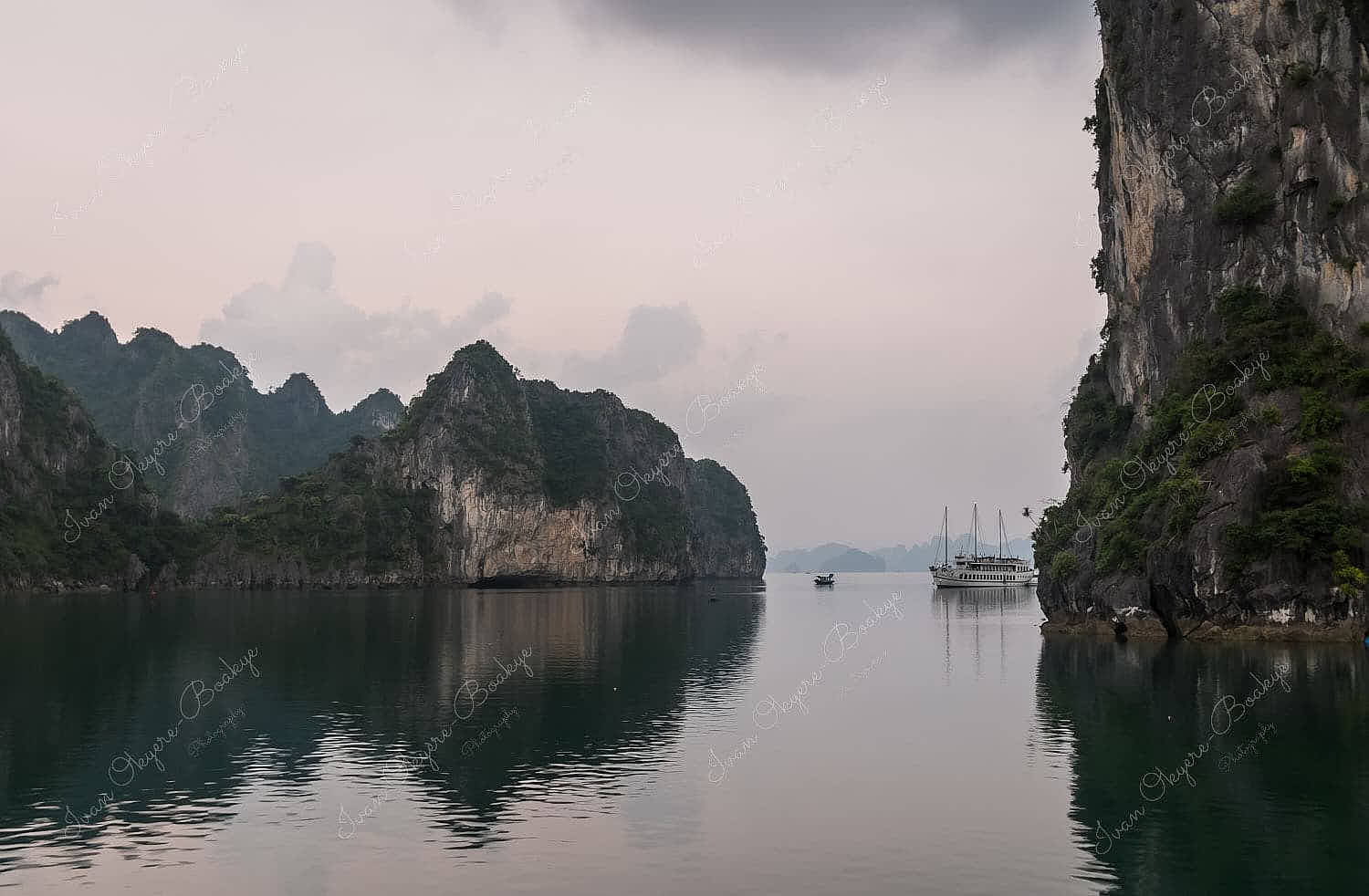 Junk boat and fishing boat between karst mountains at dawn in Halong Bay, Vietnam