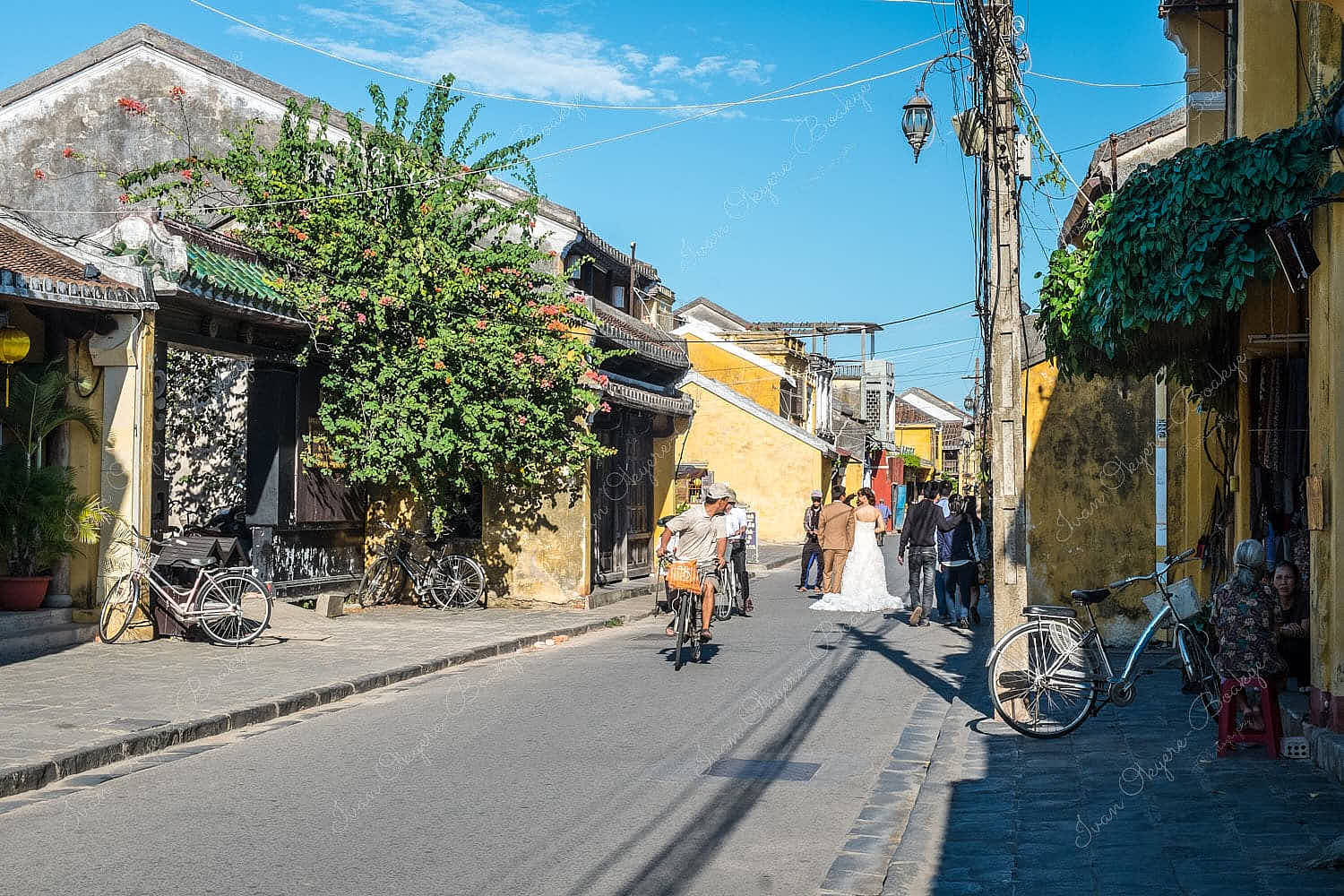 Urban photo shoot of Vietnamese bride in an elegant white wedding dress in the colourful streets of Hoi An Old Town in Vietnam