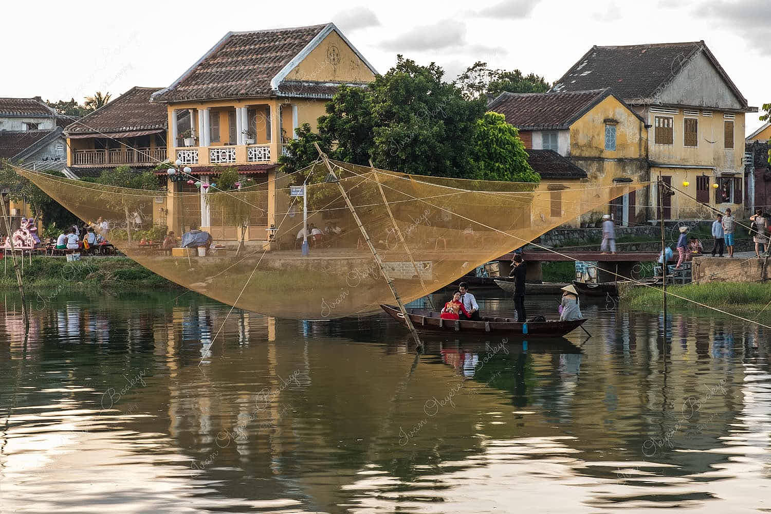 Bride and groom wedding photo shoot under a suspended fishing net in Thu Bon River at the riverfront of Old Town in Hoi An, Vietnam