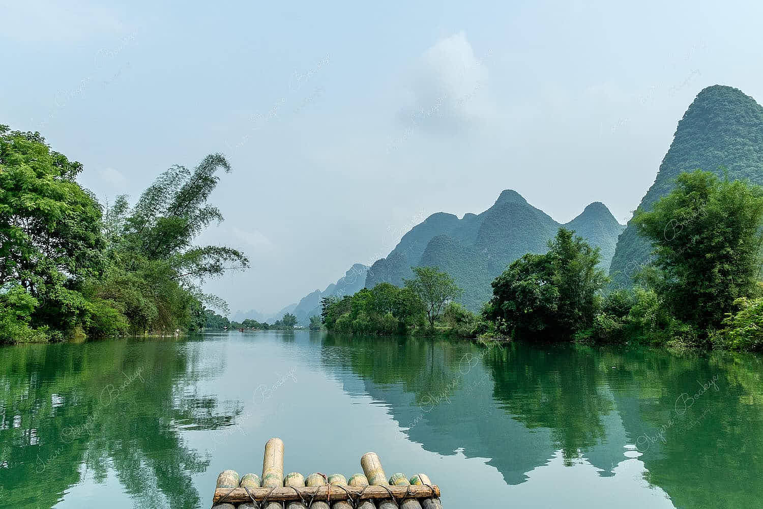 Sailing on bamboo raft on Yulong River surrounded by karst mountains and trees in Guilin, China