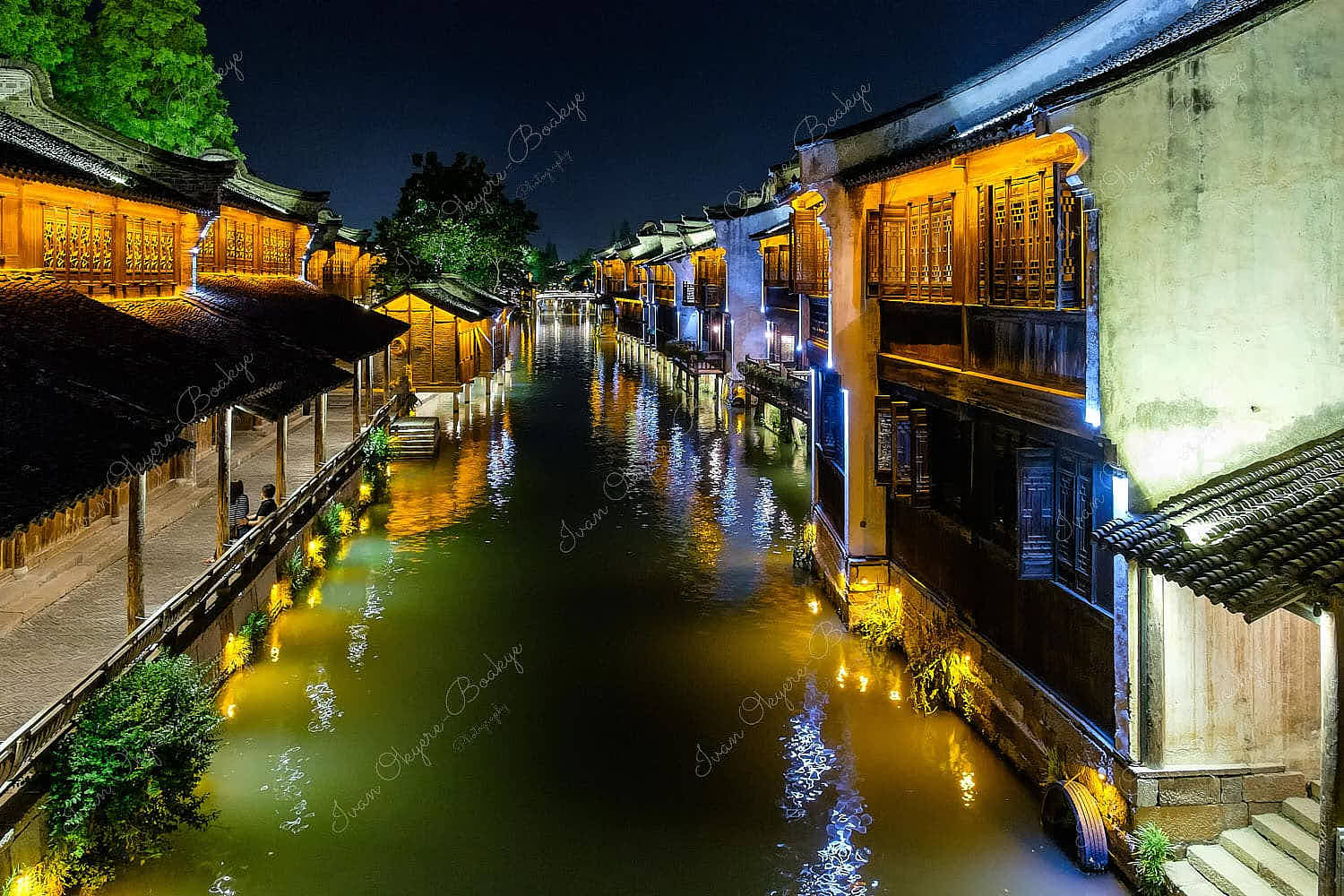 Night time view of illuminated traditional Chinese houses, canal and stone bridge in the historic scenic Wuzhen water town, China