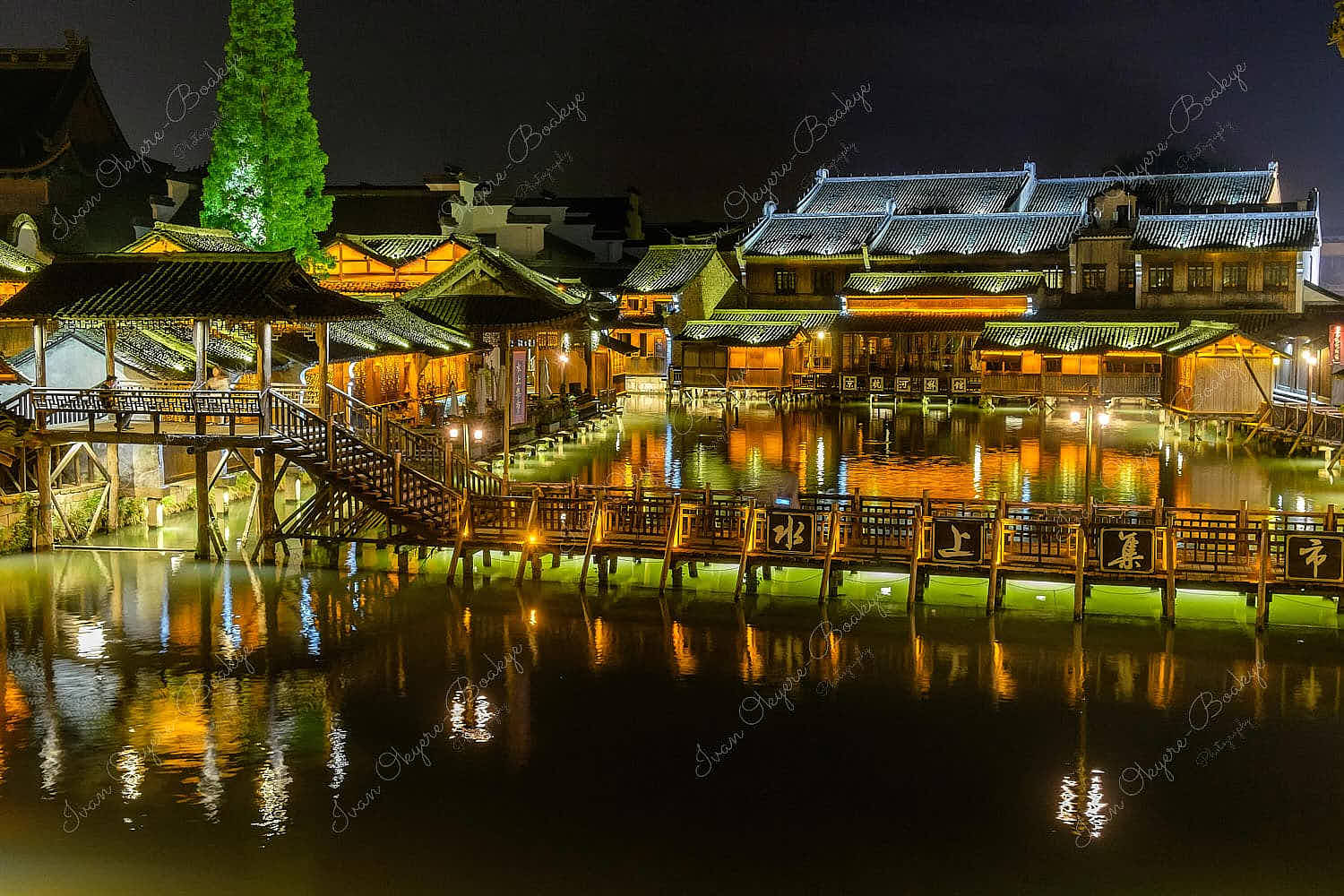 Night time view of flat wooden bridge crossing the canal surrounded by traditional Chinese houses in the historic scenic Wuzhen water town, China