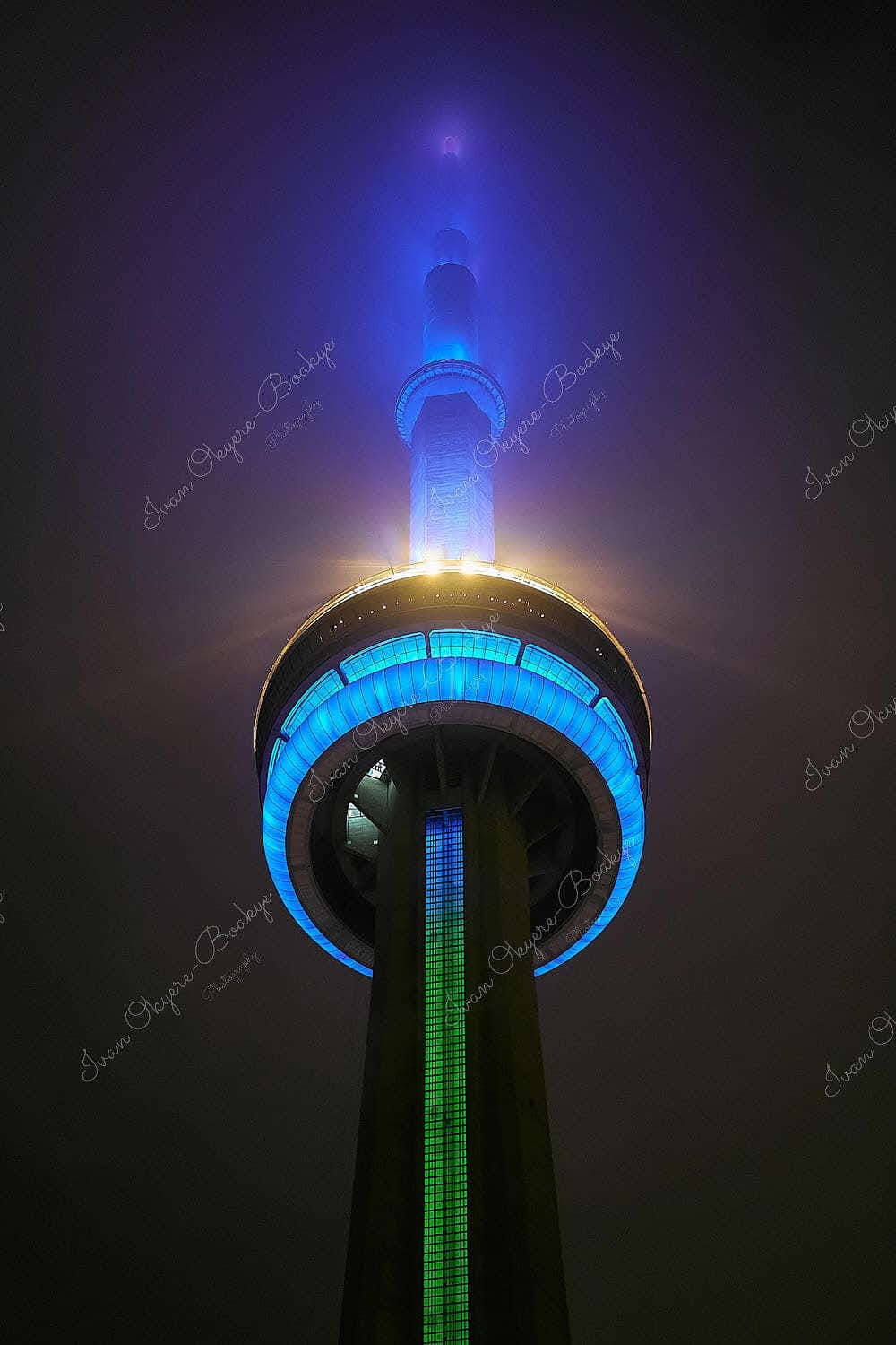 A moody looking illuminated closeup of the CN Tower on a foggy night in Toronto, Canada