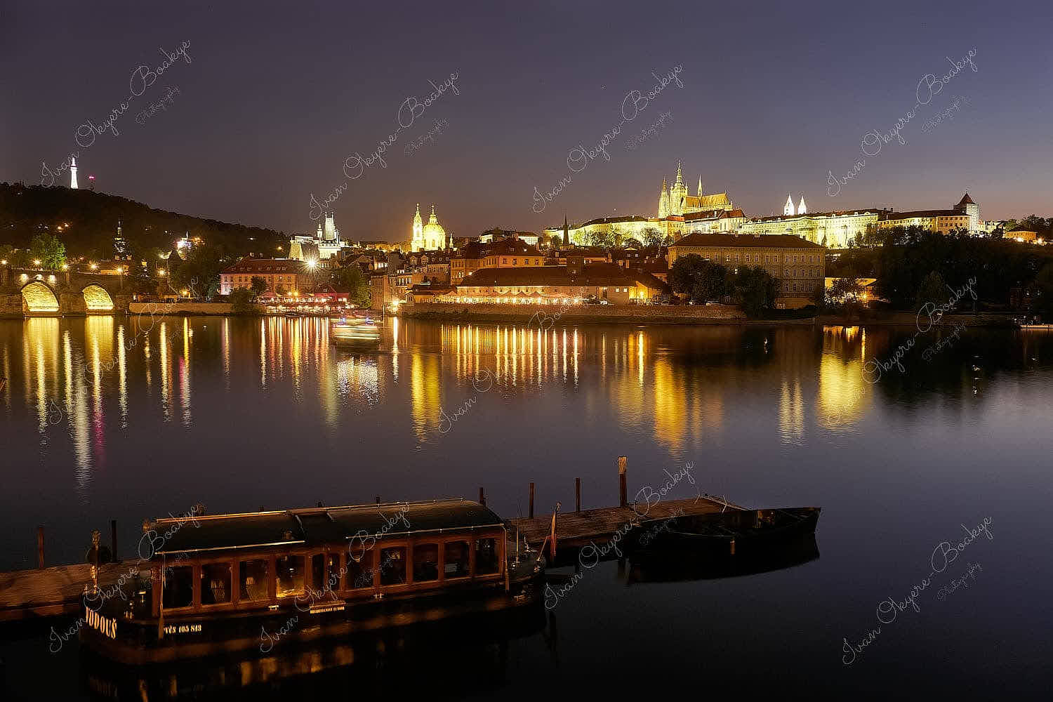 Night view of the illuminated facades of Prague Castle and St. Vitus Cathedral with reflections in the river, Prague, Czech Republic
