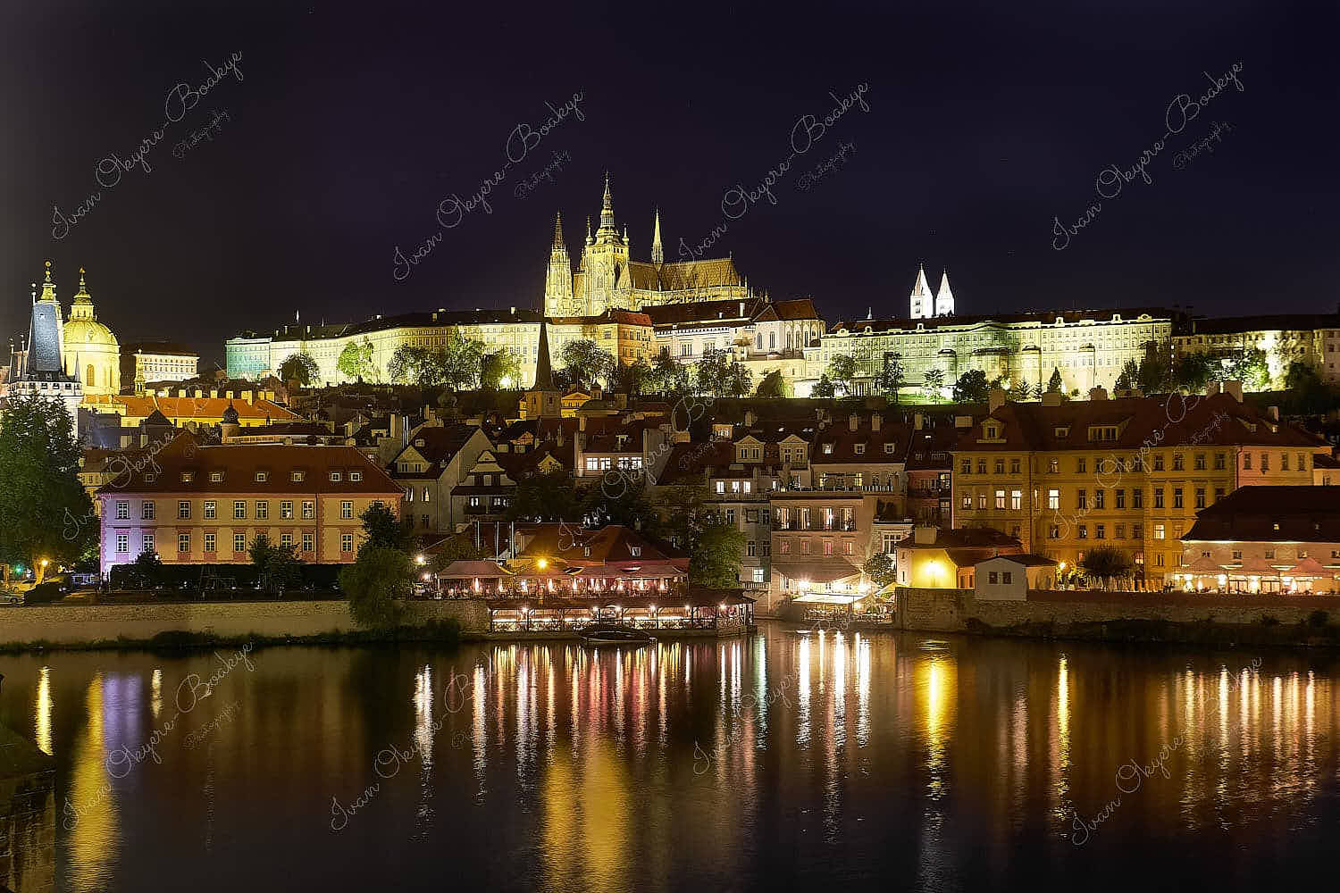 Night view of the illuminated facades of Prague Castle and St. Vitus Cathedral with reflections in the river, Prague, Czech Republic