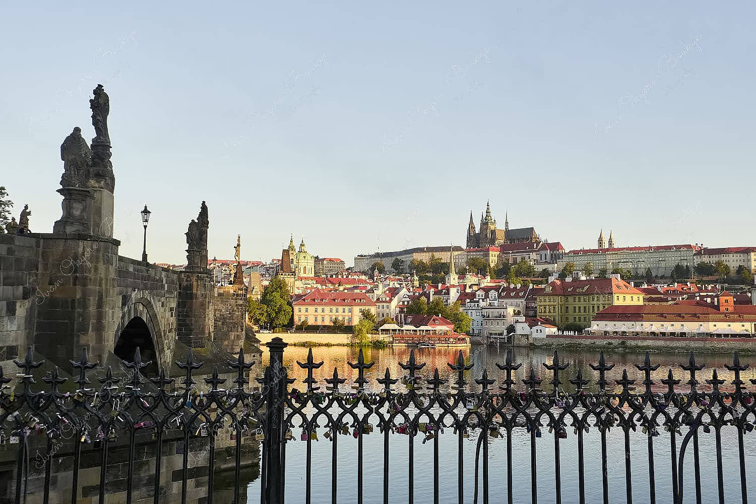 The walls of Charles Bridge leading across the river to Prague Castle and St. Vitus Cathedral at sunrise, Prague, Czech Republic