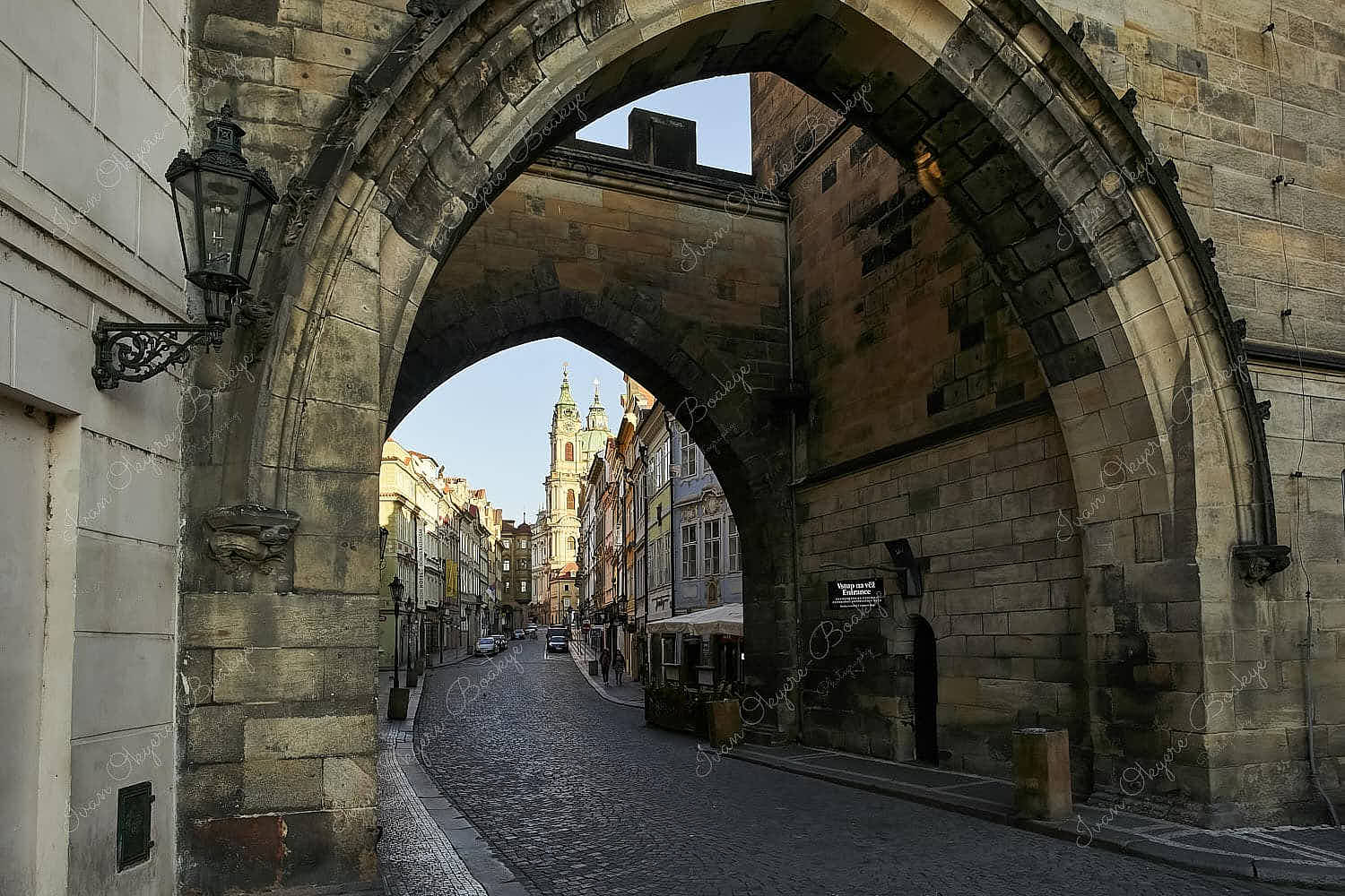 St. Nicholas Church at sunrise viewed from the arched tower entrance of Charles Bridge, Prague, Czech Republic