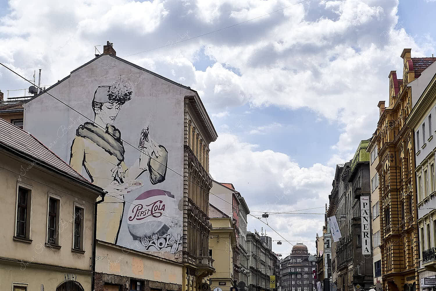 Large street mural of a woman in 1940s style womenswear and a Pepsi-Cola bottle cap painted on the side of building in Prague, Czech Republic
