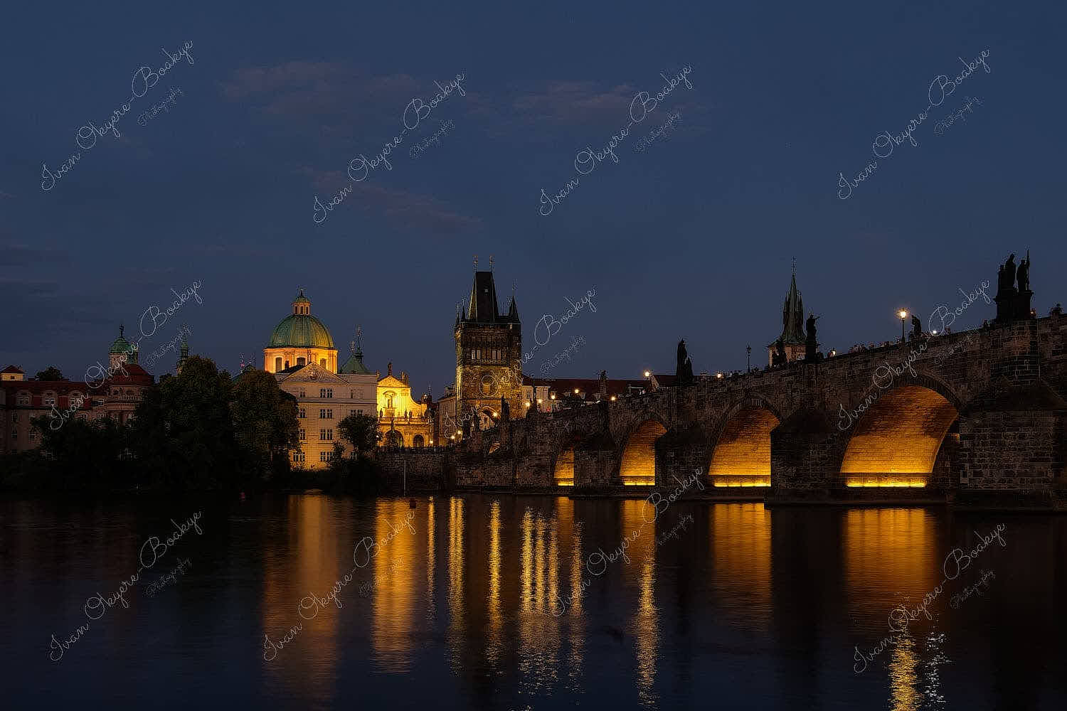 Riverside night time view of the illuminated Charles Bridge, Prague Castle and St. Vitus Cathedral in Prague, Czech Republic