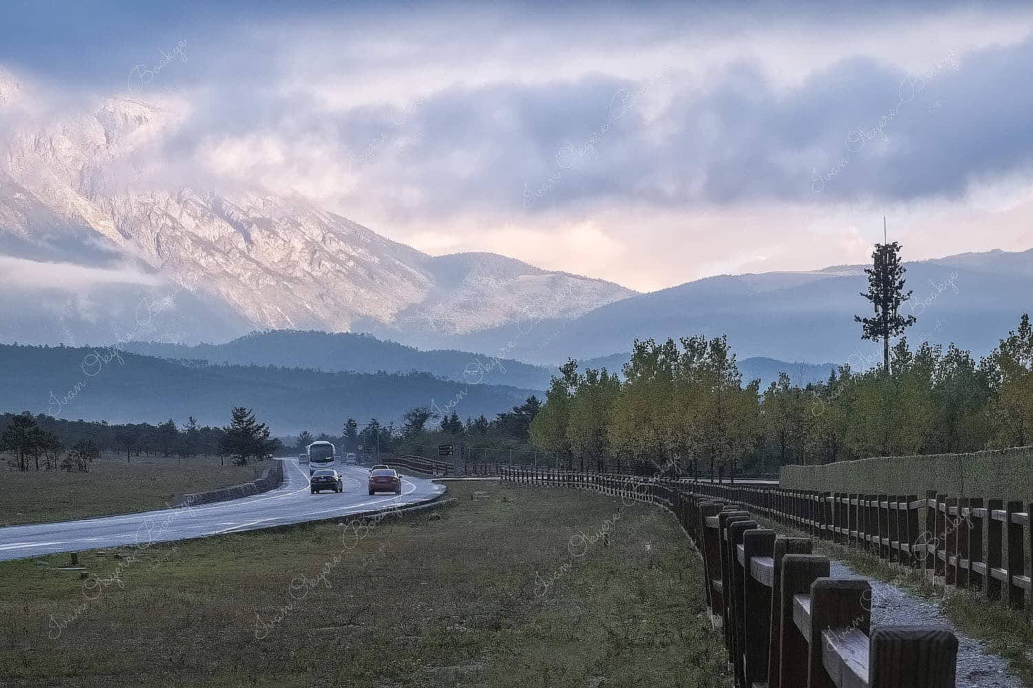 Road leading to a sunlit Jade Dragon Snow Mountain at sunrise in Lijiang, China