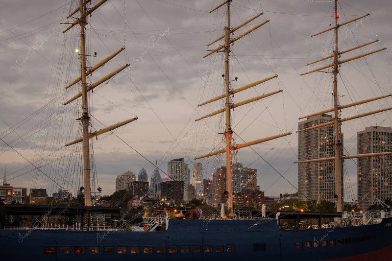 View of skyscrapers in Philadelphia skyline at night through the masts of a waterfront boat restaurant, Philadelphia, USA