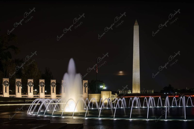 Long exposure at night of illuminated fountain at World War II Memorial with the Washington Monument in the background, Washington, USA